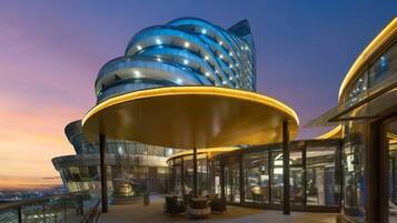 A modern building with a curved facade and a covered outdoor area with seating.