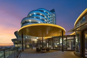 A modern building with a curved facade and a covered outdoor area with seating. - Kaihua International Hotel (Kaihua)