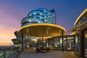 Un edificio moderno con fachada curva y un área exterior cubierta con asientos.
