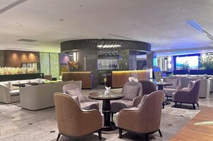 Un área de estar moderna con asientos, un bar y vistas al exterior.