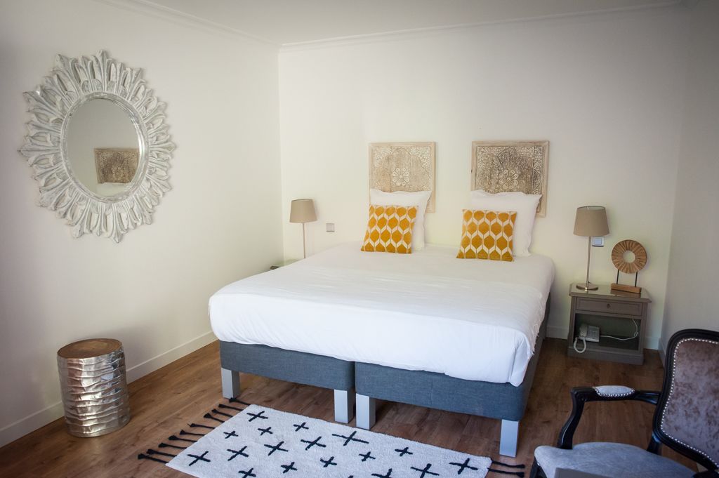 Un dormitorio con una cama, dos mesitas de noche, un espejo y una silla.