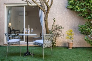 An outdoor seating area with wicker chairs and a table, a potted plant, and a sliding glass door leading to an interior space.