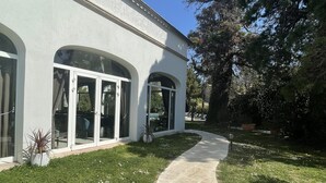 Ein modernes Gebäude mit großen Bogenfenstern und einem gepflasterten Weg, der zu einem Poolbereich führt.