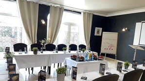 Ein Konferenzraum mit einem langen Tisch, der für eine Besprechung gedeckt ist, umgeben von Stühlen, einer Whiteboard-Tafel und informativen Postern an den Wänden.