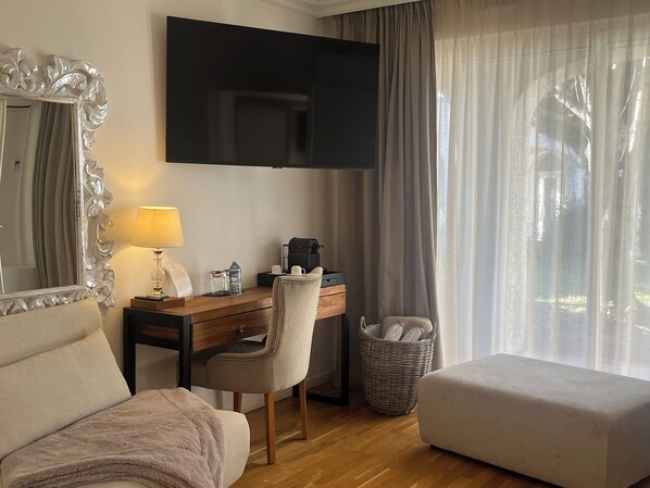 A hotel room with a bed, a desk with a chair, a television, and a window with curtains.
