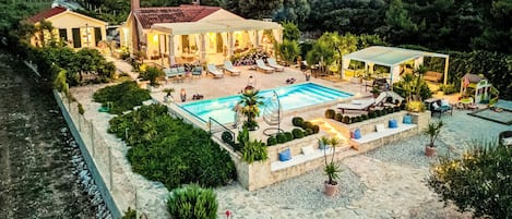 A luxurious villa with a swimming pool, outdoor seating, and a garden.