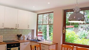 A kitchen with white cabinets, a stove, and a window overlooking a garden. - Karpacz Kowary by Interhome (Karpacz)