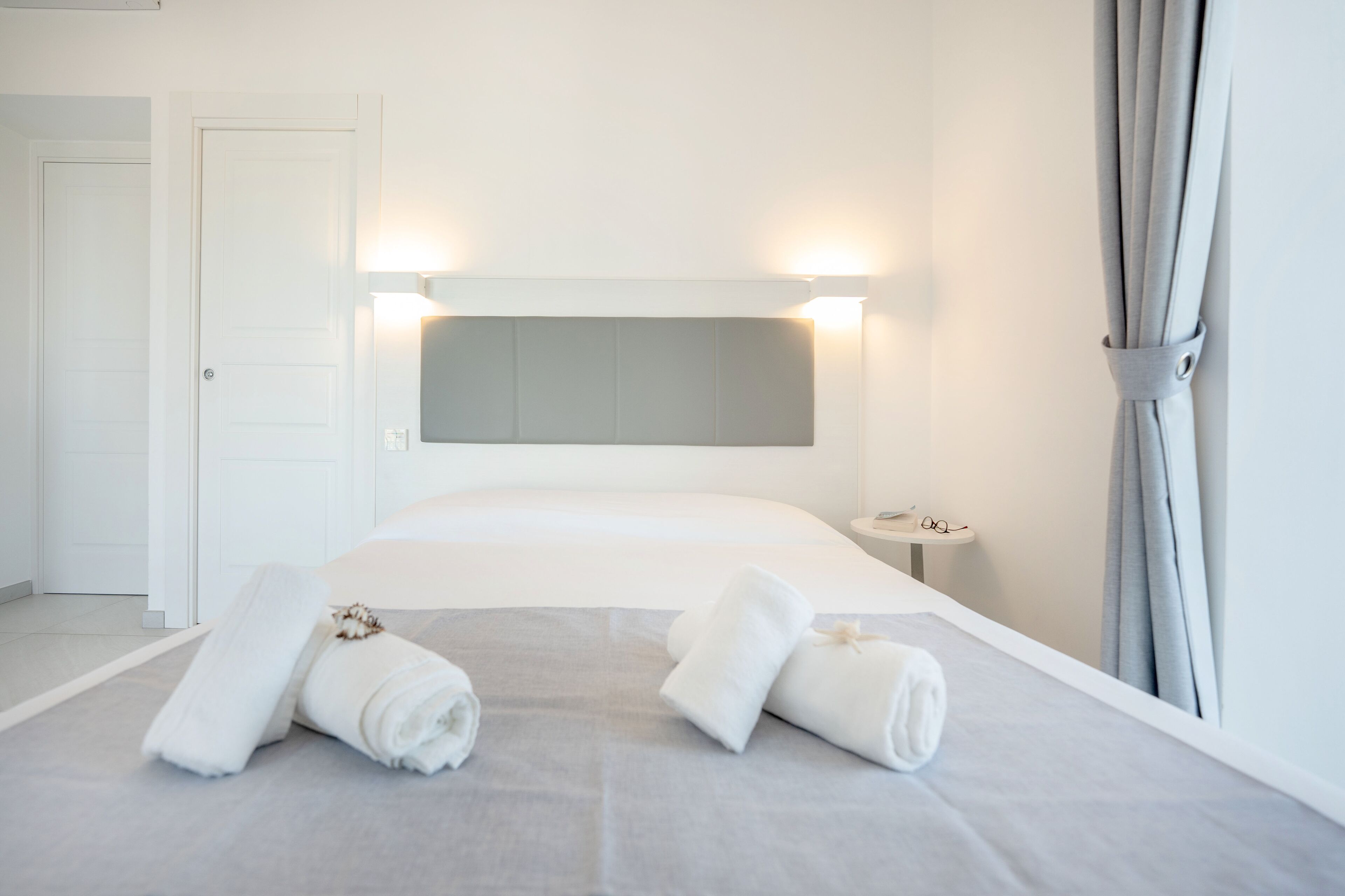 A hotel room with a large bed, a bedside table, and a mirror.