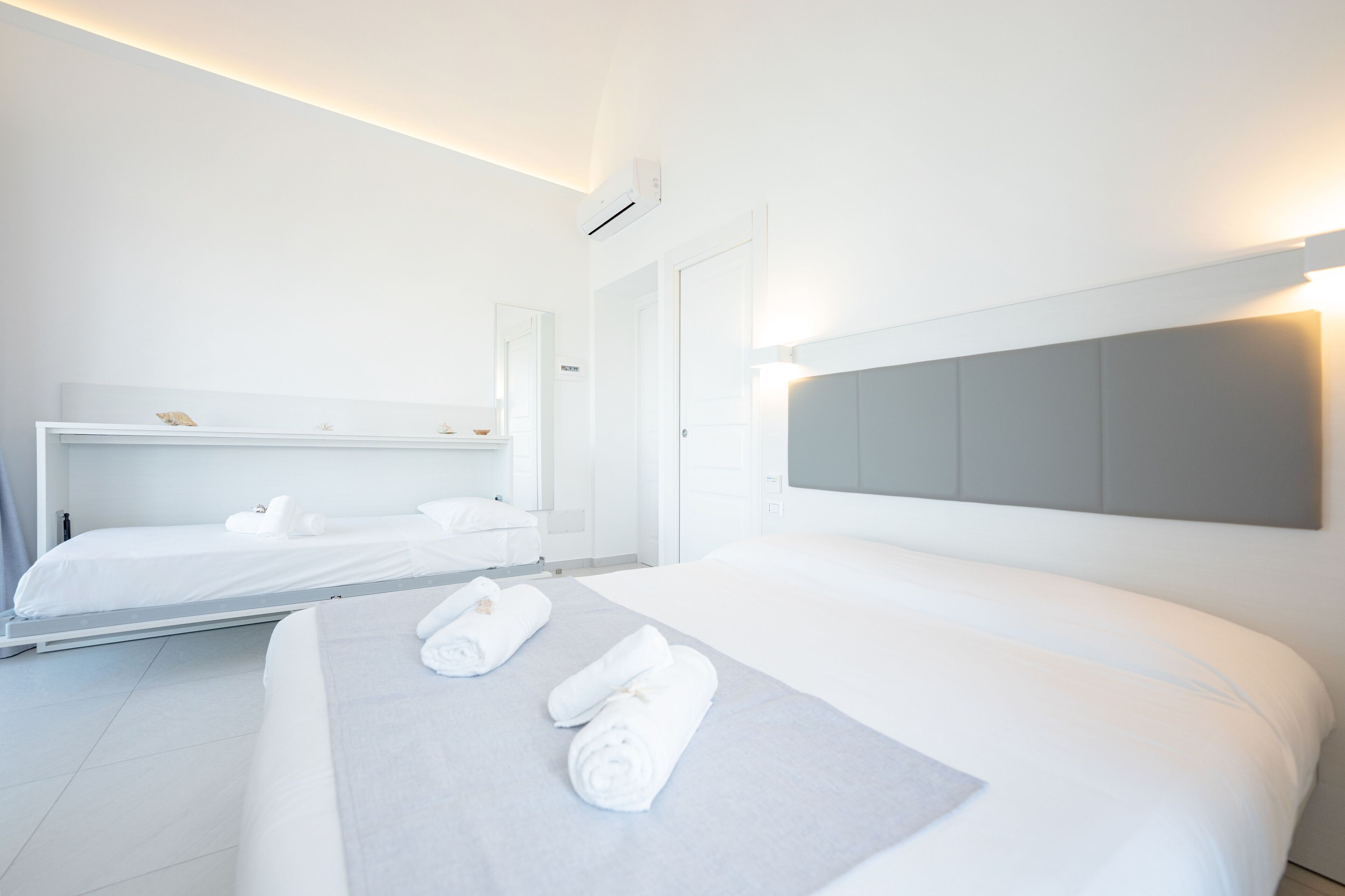 Una habitación de hotel moderna con una cama grande, una cama más pequeña y un vestidor.