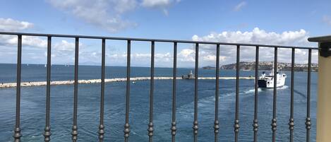 A coastal view with a metal railing, a body of water, and a boat.