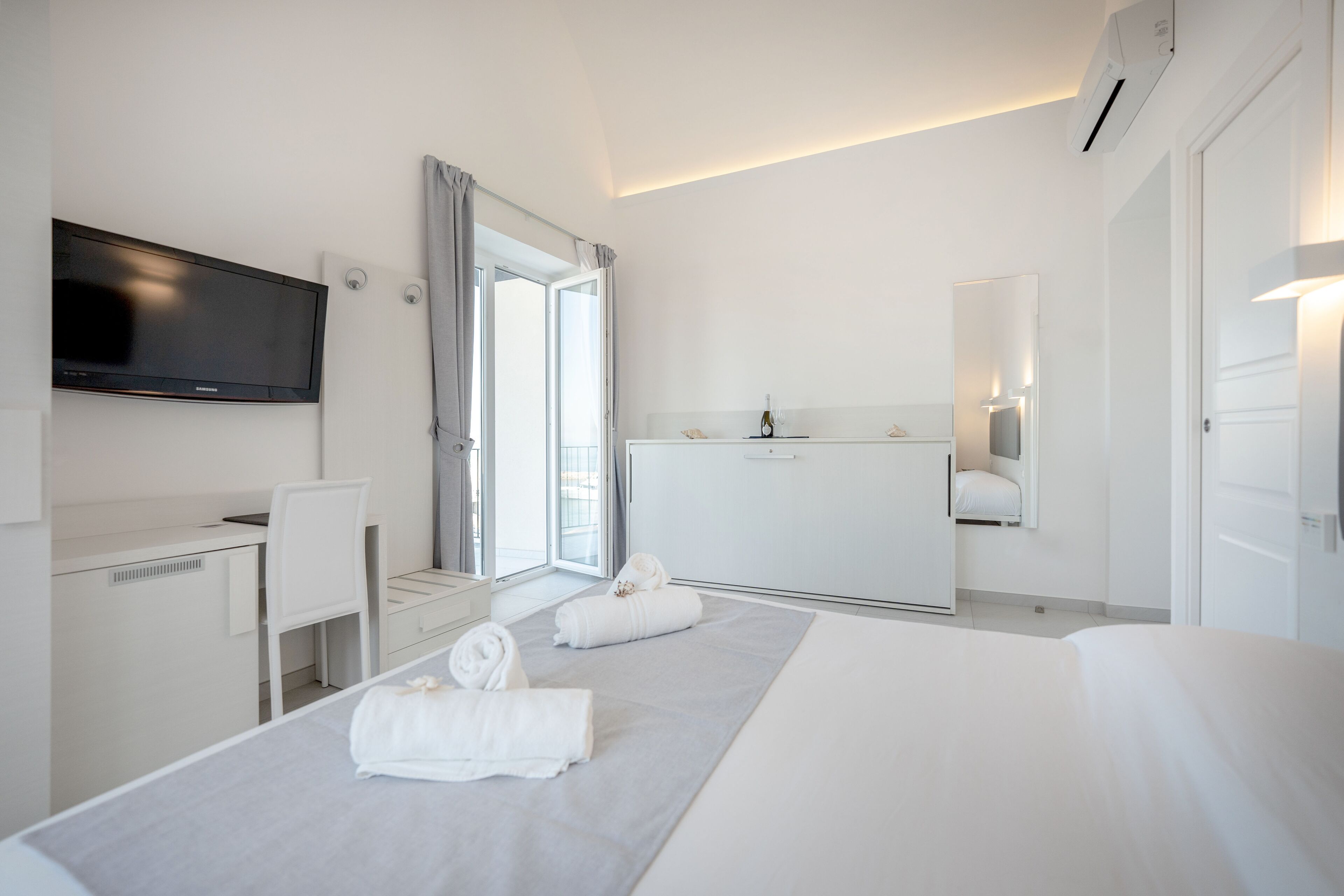 Een moderne hotelkamer met een bed, bureau, televisie en een badkamer.
