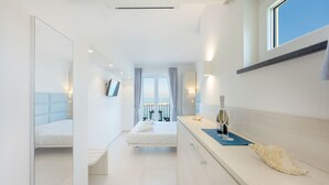 Habitación de hotel moderna con una cama grande, un escritorio con ordenador y vistas al mar.