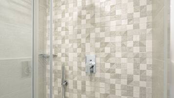 Dusche mit Glastür, Regendusche und einer gefliesten Wand mit geometrischem Muster.