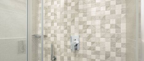 A shower with a glass door, a rain showerhead, and a tiled wall with a geometric pattern.