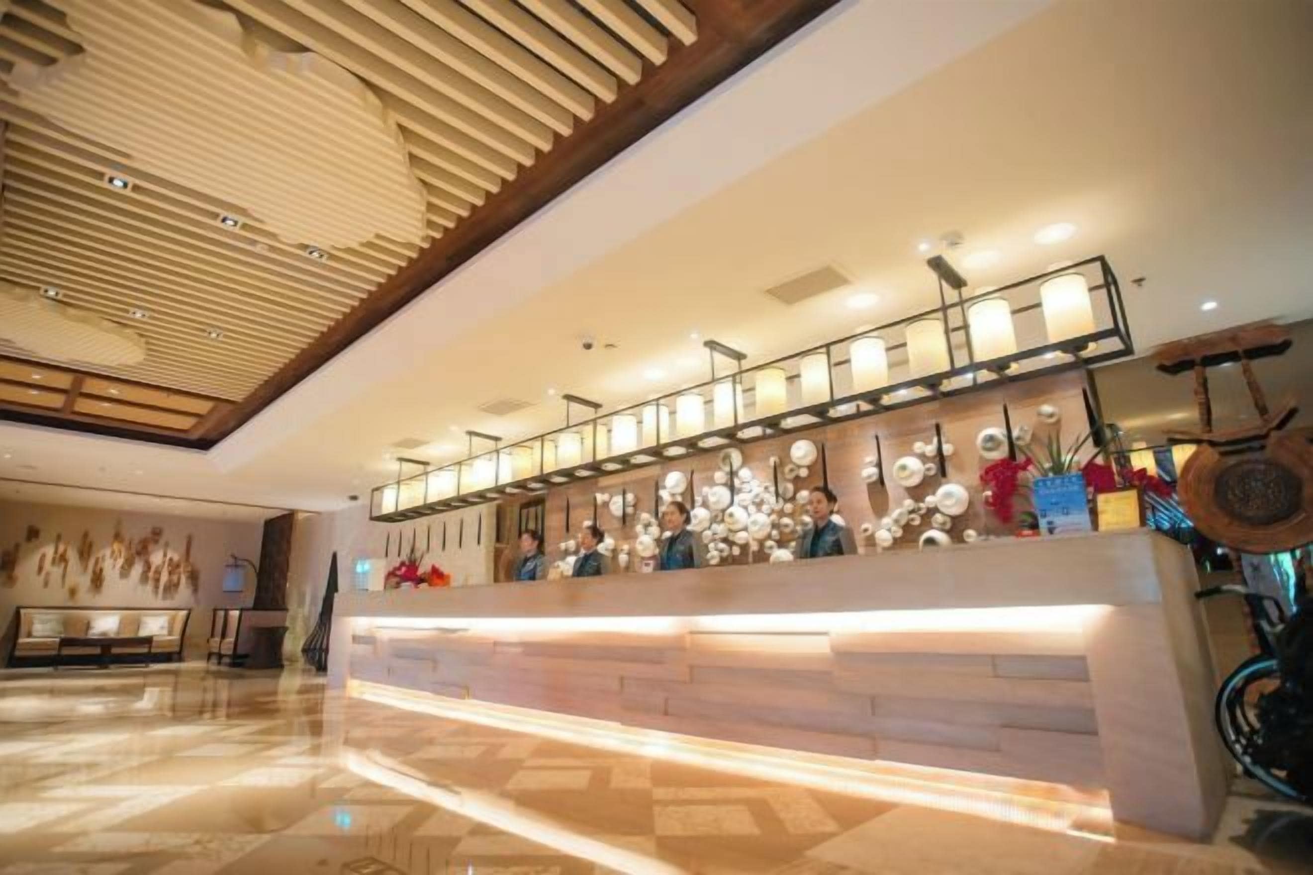 A hotel reception area with a modern design, featuring a reception desk, seating area, and a decorative ceiling.