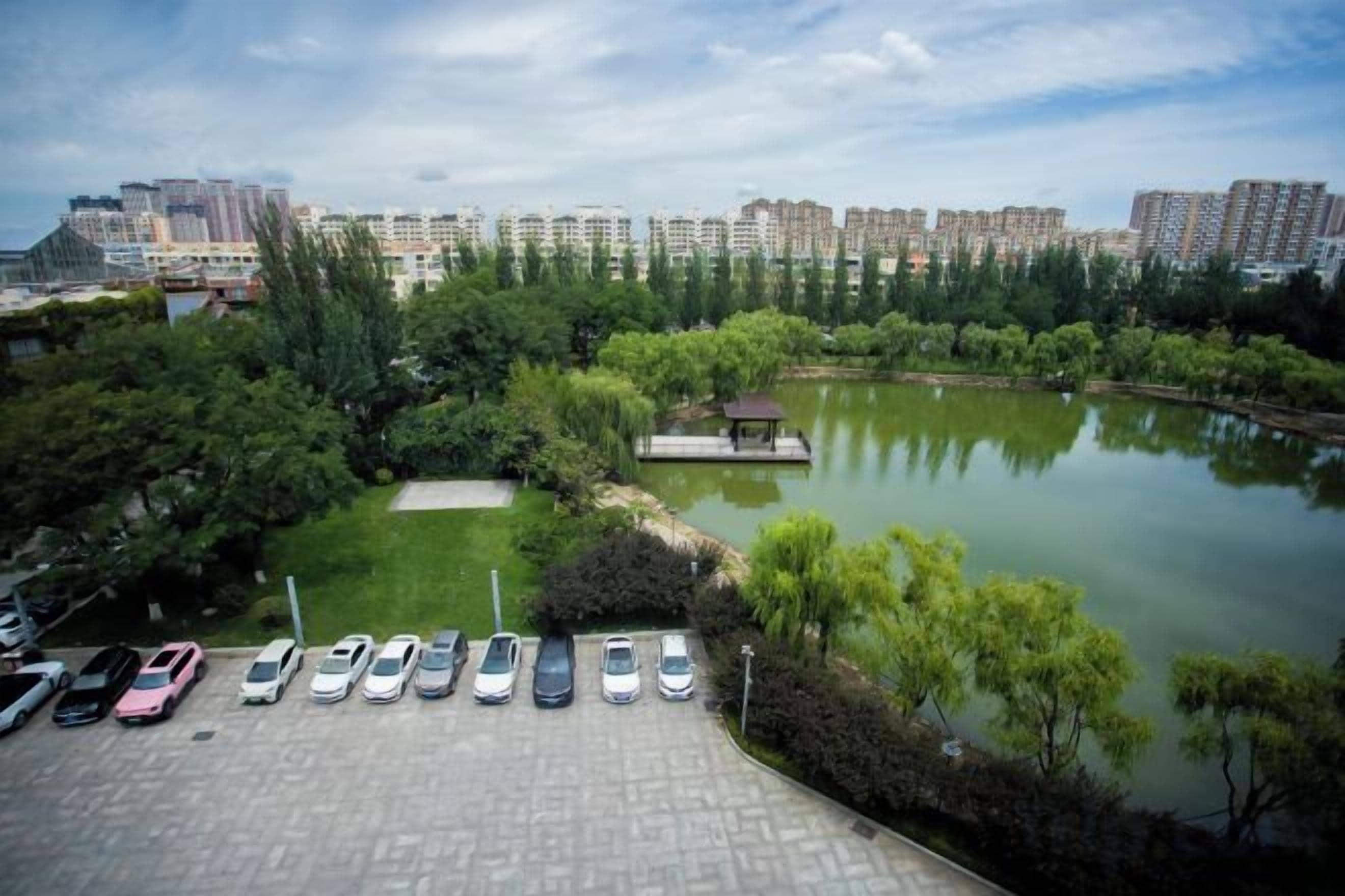 A parking area with cars, a pond, and a gazebo.