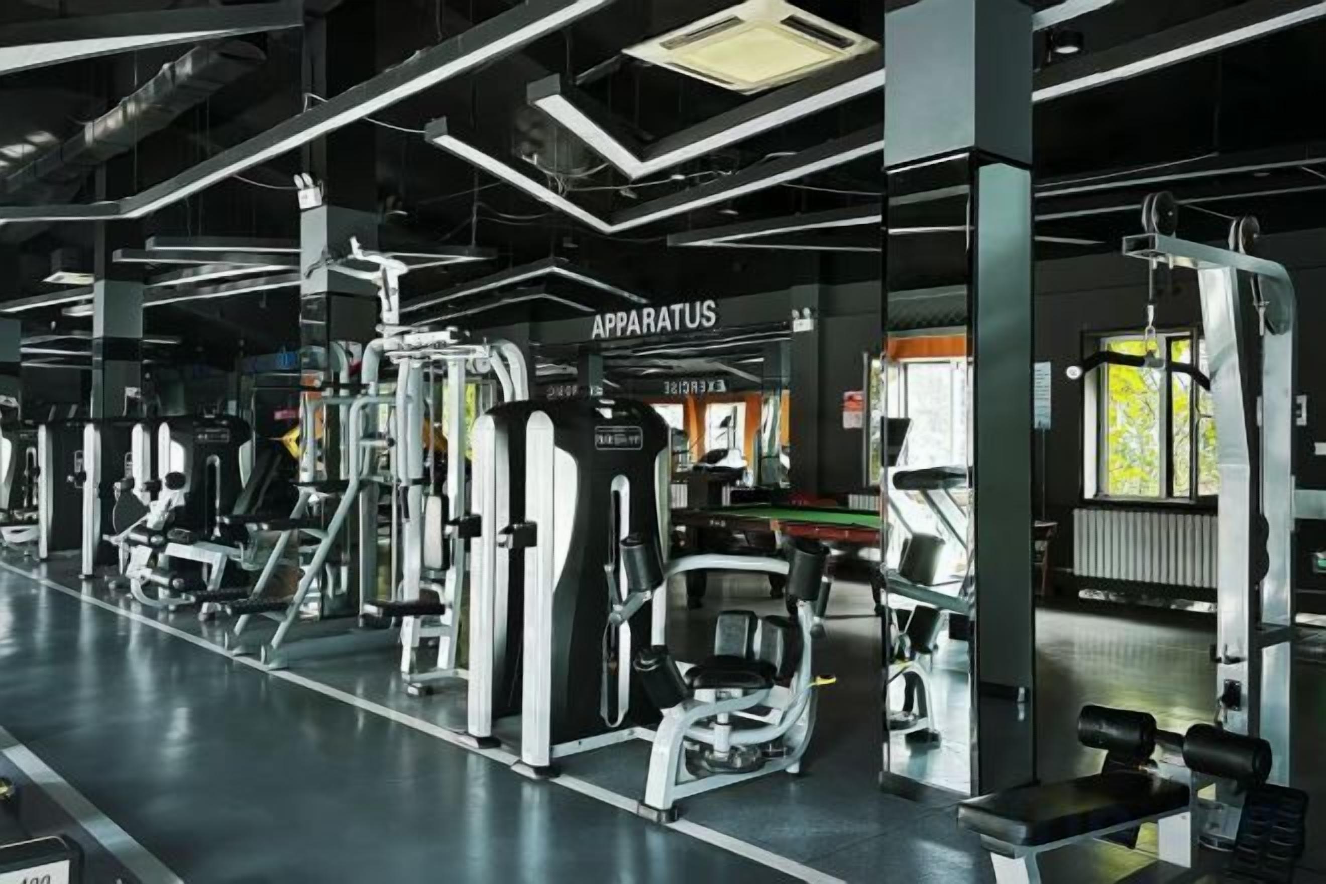 Un gimnasio con diferentes máquinas de ejercicio y una zona de cintas de correr.