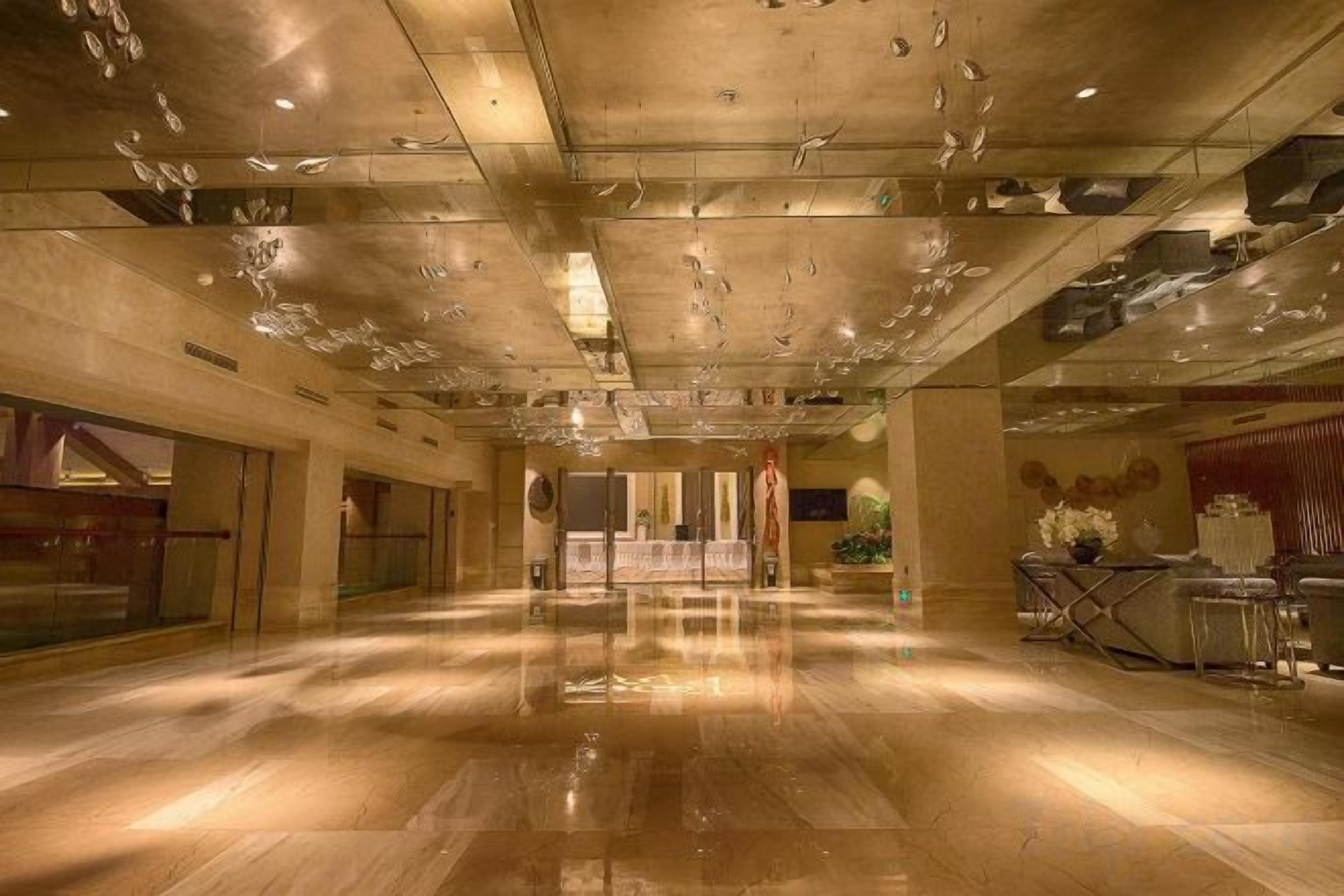 Un hall d’hôtel spacieux, doté d’un sol ciré, d’un comptoir de réception et d’un espace détente avec des sièges.