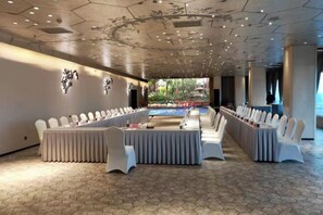 A long table with white chairs, a hexagonal floor pattern, and a view of a garden through a glass wall. - Panjin Ecological Hotel (PANJINU)