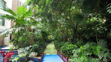 A lush indoor garden with a blue pathway leading to a seating area.
