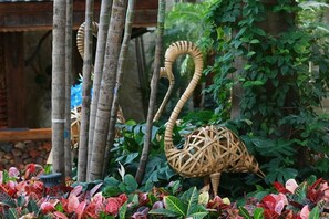 Une sculpture de cygne décorative dans un jardin agrémenté de bambous et de feuillage.