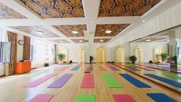 Un amplio estudio de yoga con suelos de madera, esterillas de yoga coloridas y un techo decorativo.
