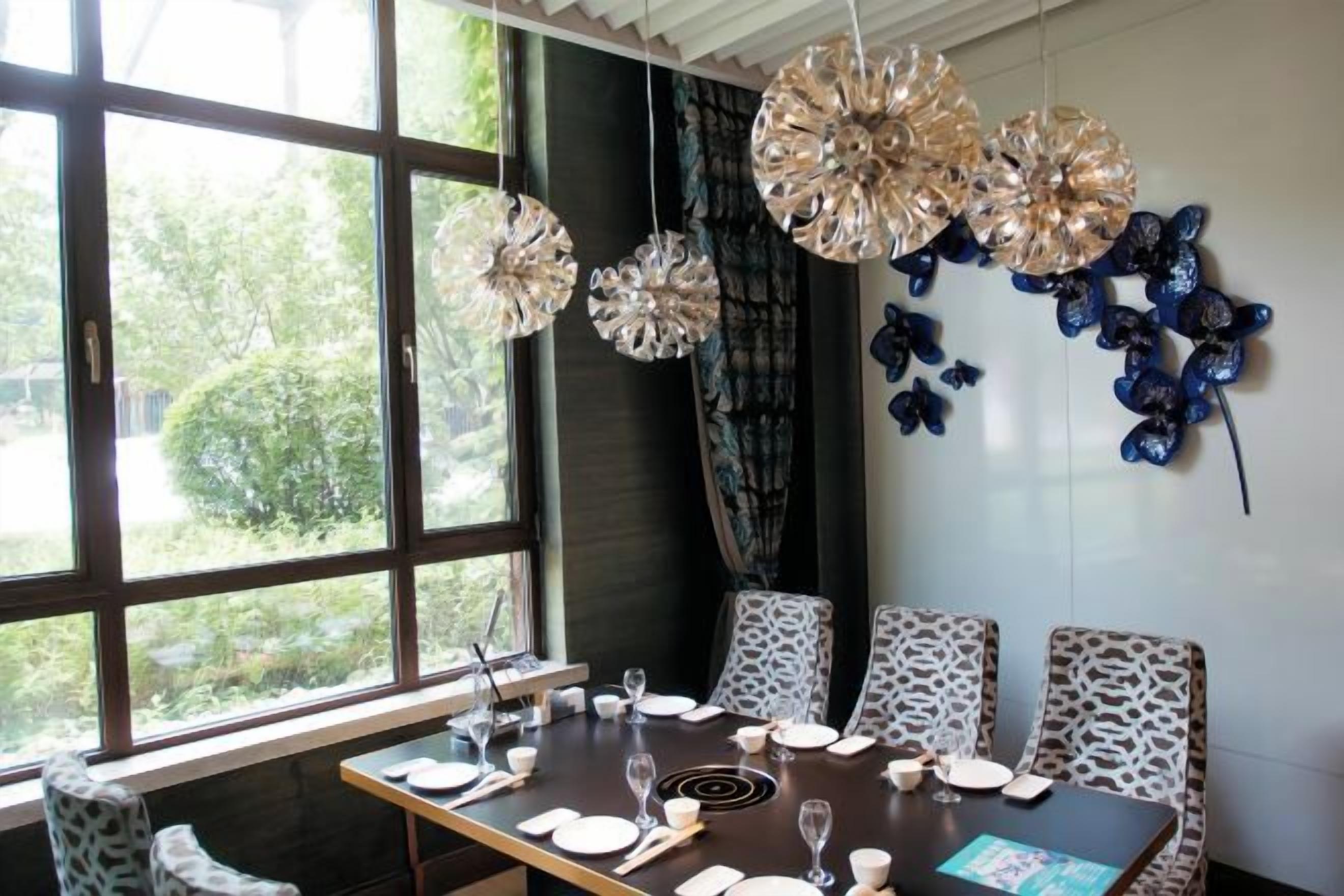 Un comedor con una mesa lista para cuatro, una ventana con vistas a la vegetación y decoración en la pared.