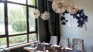 Un comedor con una mesa lista para cuatro, una ventana con vistas a la vegetación y decoración en la pared.