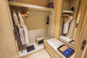A compact bathroom with a walk-in closet, a small vanity, and a mirror. - Panjin Ecological Hotel (PANJINU)