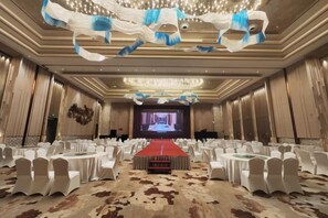 A conference room with a red carpet, white chairs, and a large screen at the front. - Panjin Ecological Hotel (PANJINU)