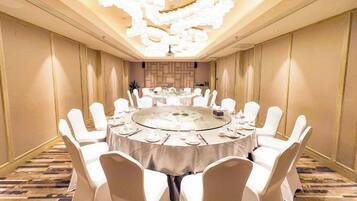 A conference room with a round table, white chairs, and a chandelier.