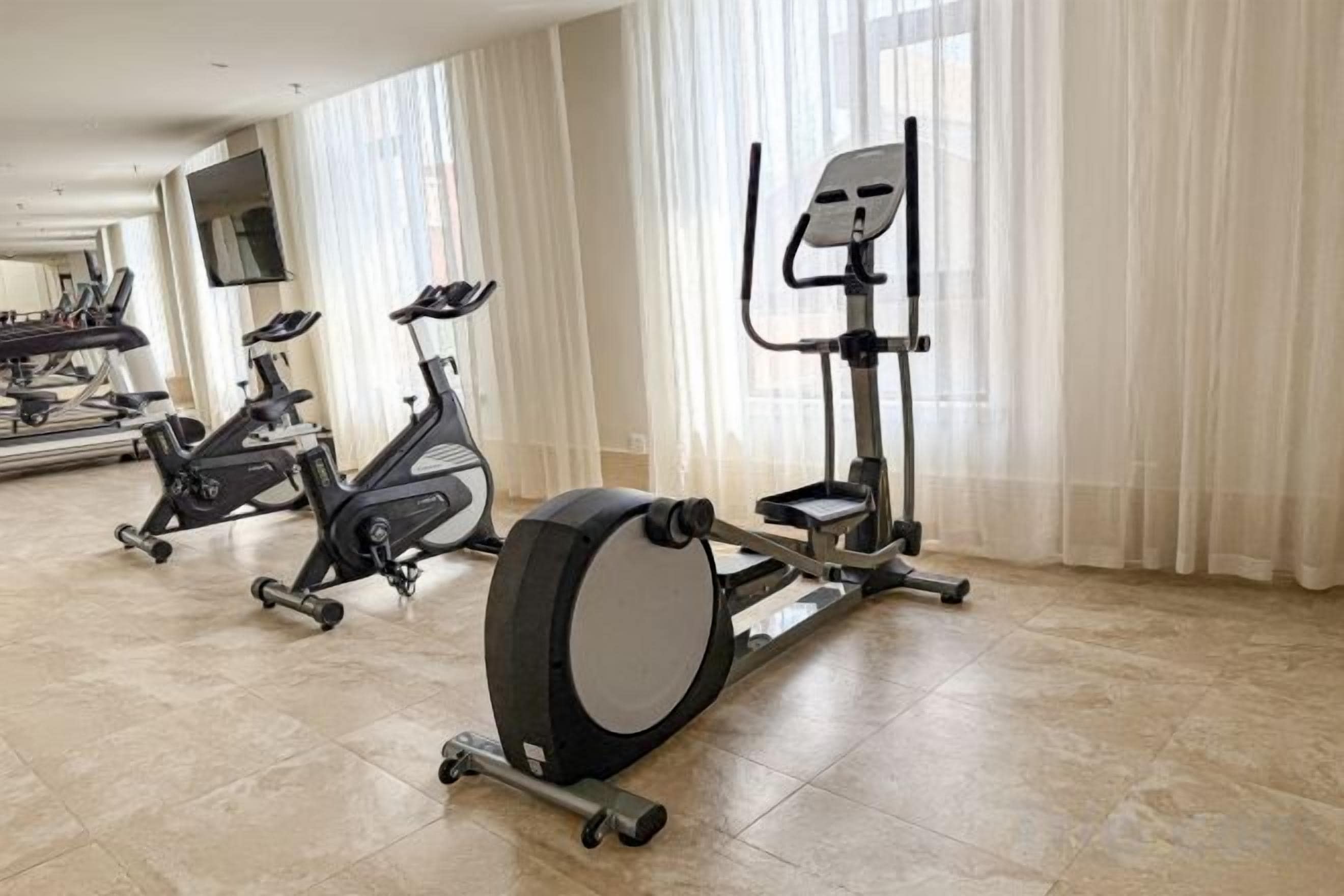 Un gimnasio en casa con bicicletas estáticas, una elíptica y una cinta de correr.