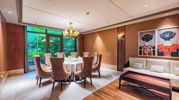 A dining area with a round table and chairs, a chandelier, and a sofa with cushions.