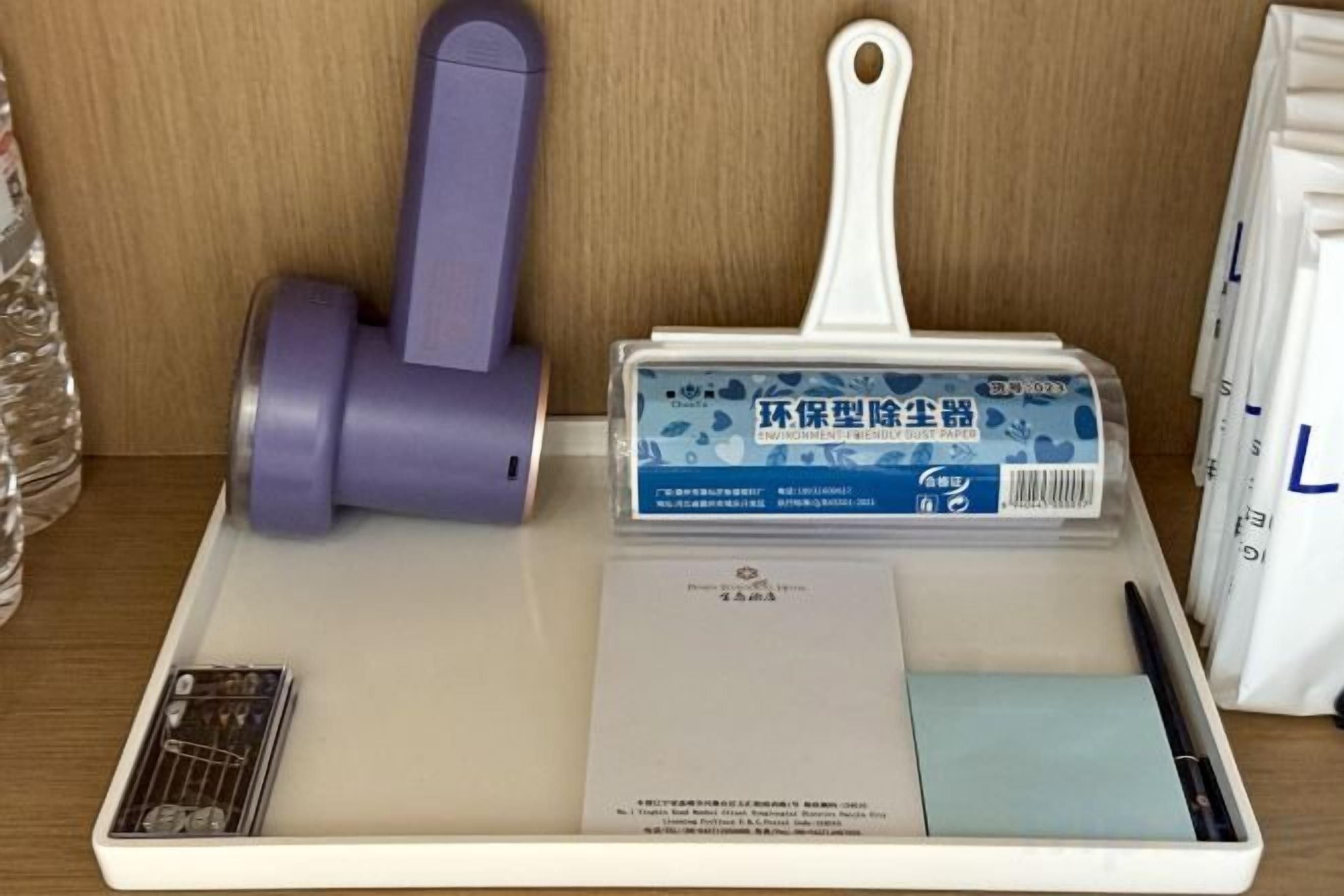 Un plateau contenant un objet aux couleurs violet et blanc, une boîte bleue et un paquet blanc.