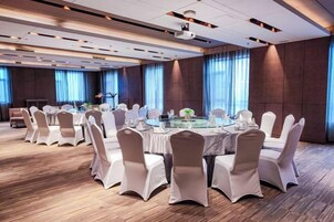 A conference room with round tables, white chairs, and a projector screen.