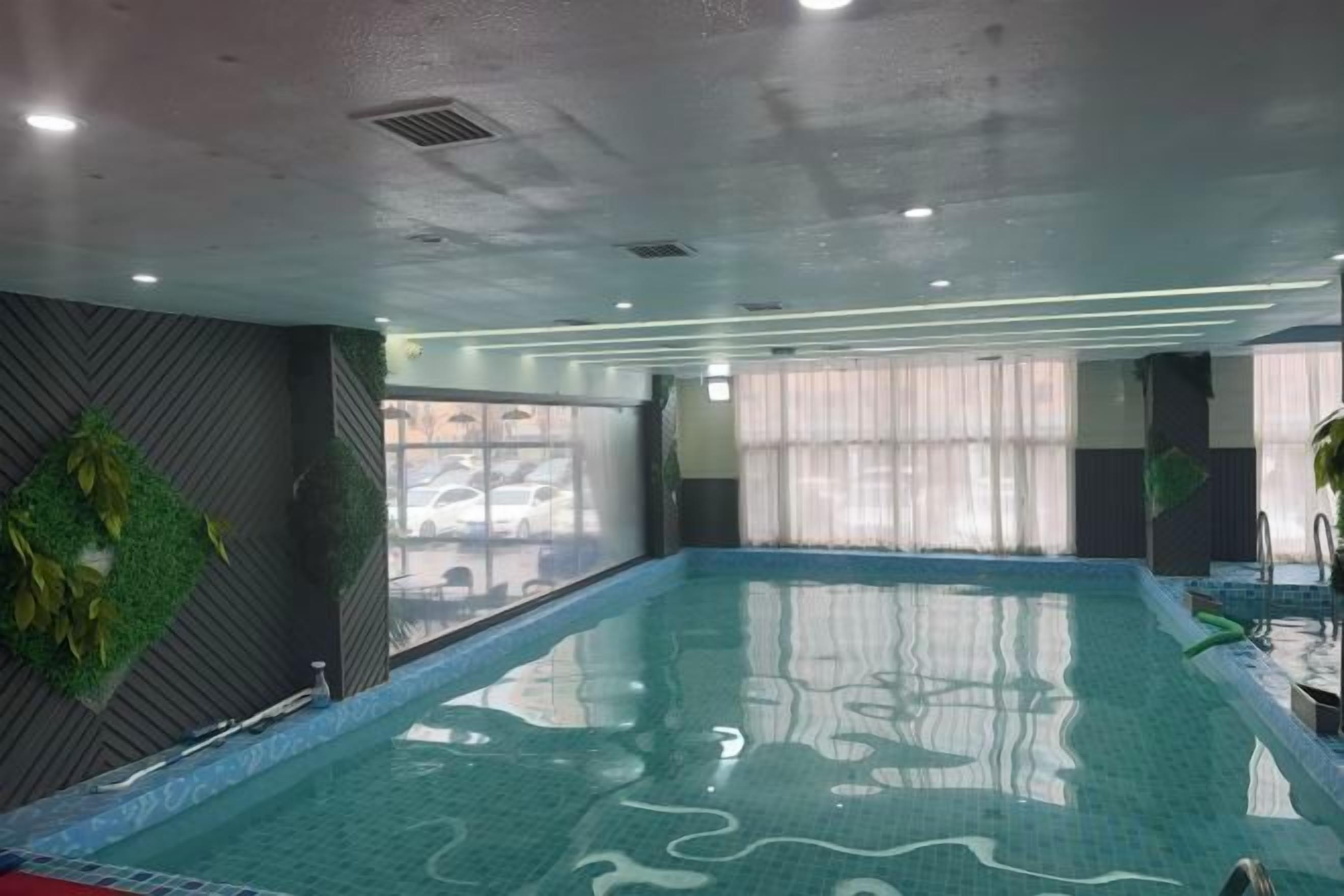 Una piscina interior con vistas amplias al exterior a través de grandes ventanales.