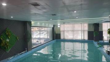 Una piscina interior con vistas amplias al exterior a través de grandes ventanales.