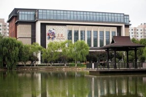 A building with a large glass facade, a pavilion, and a body of water in front. - Panjin Ecological Hotel (PANJINU)