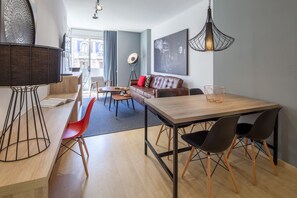 Ein modernes Wohnzimmer mit Essbereich, ausgestattet mit einer Couch, einem Couchtisch und einem Esstisch mit Stühlen.