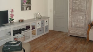 A room with a television, a vase with flowers, a cabinet with storage drawers, and a wardrobe. - LA GARIGUETTE APARTMENT NEAR NIMES (Uchaud)