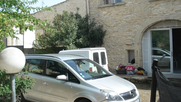 A silver car parked in front of a stone building with a large window and a door. - LA GARIGUETTE APARTMENT NEAR NIMES (Uchaud)