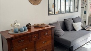 Una sala moderna con un sofá gris, un aparador de madera y dos tapices de fibras naturales.