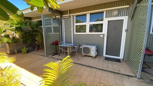 Un patio con mesa y sillas, una parrilla y un equipo de aire acondicionado.