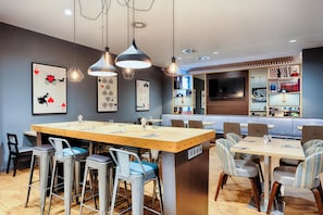 A restaurant with a bar area, multiple seating options including high stools and chairs, and a variety of wall decorations. - Premier Inn Leipzig City Centre (Leipzig)