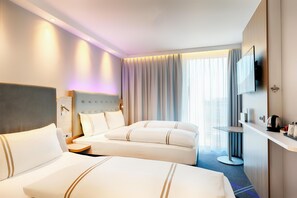 Een hotelkamer met twee bedden, een televisie, een bureau en een groot raam met gordijnen.