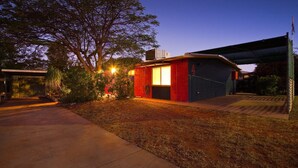 Ein modernes Haus mit Garage, überdachter Terrasse und einem großen Baum im Hintergrund.