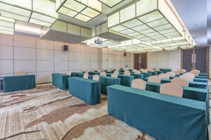 A conference room with rows of tables and chairs, a patterned carpet, and a high ceiling with skylights. - Huaxin Hotel (XIANNING)