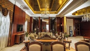 Una habitación lujosa con un sofá grande y decorado, una mesa de comedor y una araña.