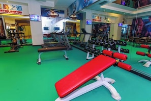 A gym with treadmills, dumbbells, and a red bench. - Huaxin Hotel (XIANNING)