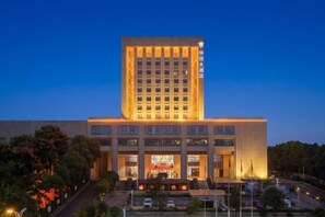 A multi-story building with a prominent entrance and a large sign above the main entrance. - Huaxin Hotel (XIANNING)